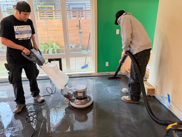 Two Olsen Restoration technicians running a rotary floor machine and wet vacuum on a hard floor